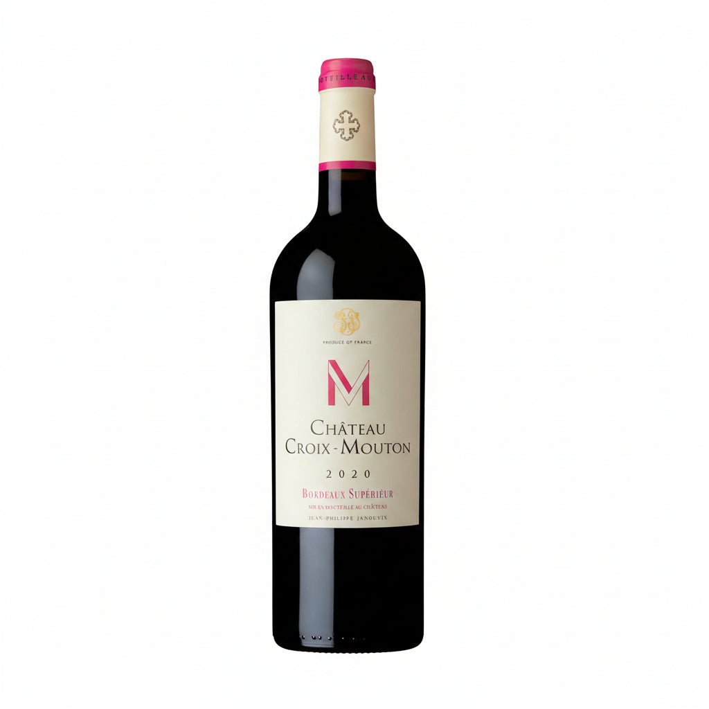 Chateau Croix Mouton 2020 bottle with label, showcasing deep red wine in a glass on a wooden table.
