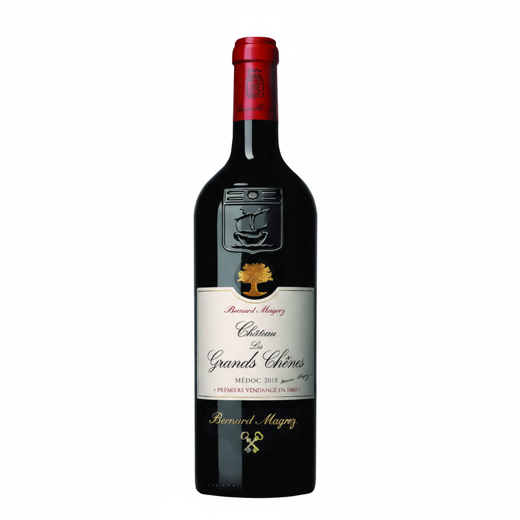 Bottle of Chateau Les Grands Chenes 2015 red wine with a classic label and cork, presented in a wine glass.