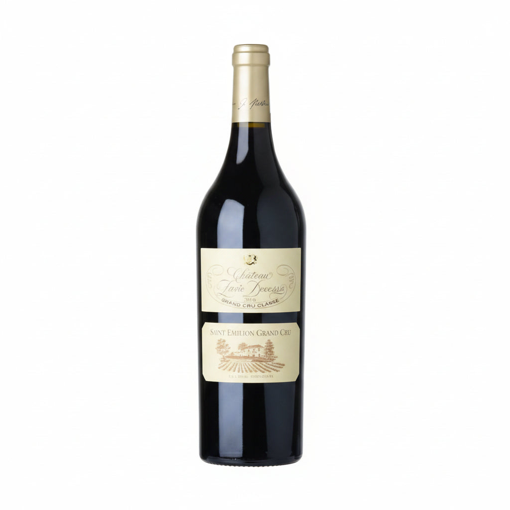 Bottle of Chateau Pavie Decesse 2016 red wine with label visible, in a wine glass on a wooden surface.