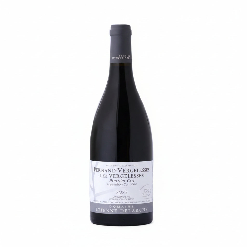 Bottle of Domaine Etienne Delarche Pernand-Vergelesses Les Vergelesses Premier Cru white wine on a wooden surface.