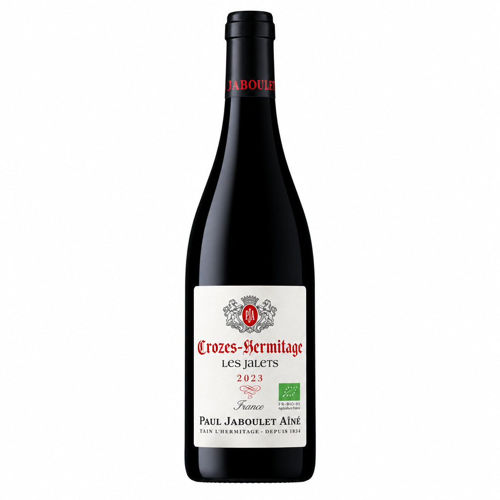 Bottle of Domaine Paul Jaboulet Aine Crozes-Hermitage Les Jalets red wine on a wooden surface with a blurred background.