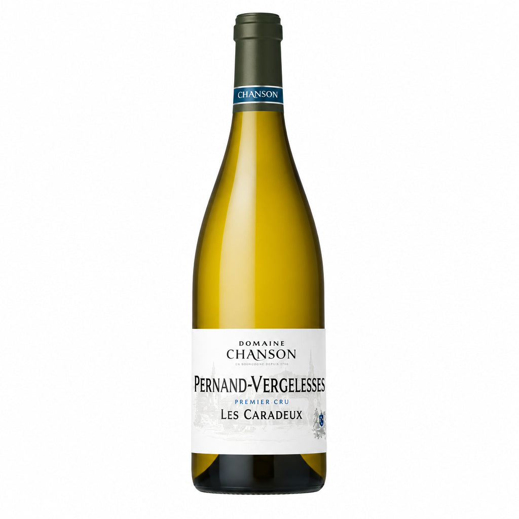 Domaine Chanson Pernand-Vergelesses Premier Cru Les Caradeux white wine bottle on a wooden surface with a blurred vineyard background.
